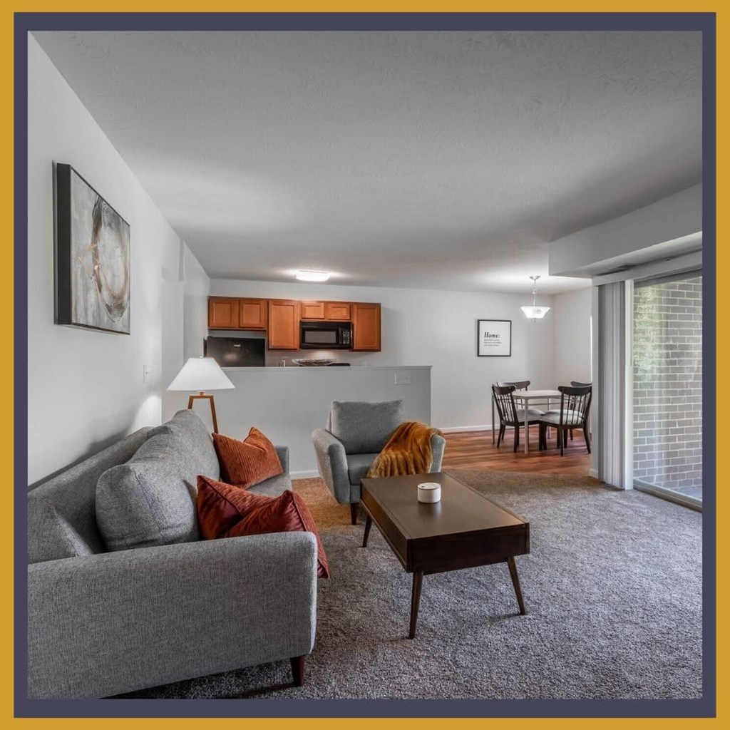 A living room with a grey couch, a coffee table, and a dining table with chairs.