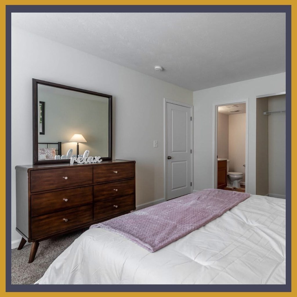 A bedroom with a bed, dresser, and mirror.