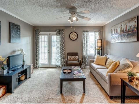 A living room with a couch, a coffee table, a television, and a ceiling fan.