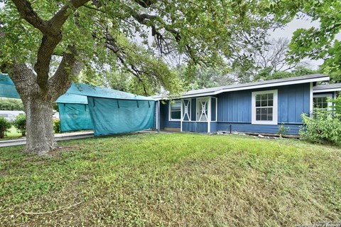 A blue house with a green tarp covering the windows.