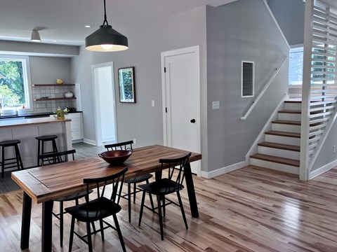 A kitchen with a table and chairs in the foreground and a staircase in the background.