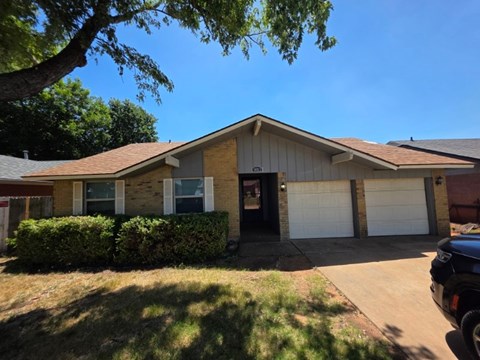 A house with a garage and a tree in front.
