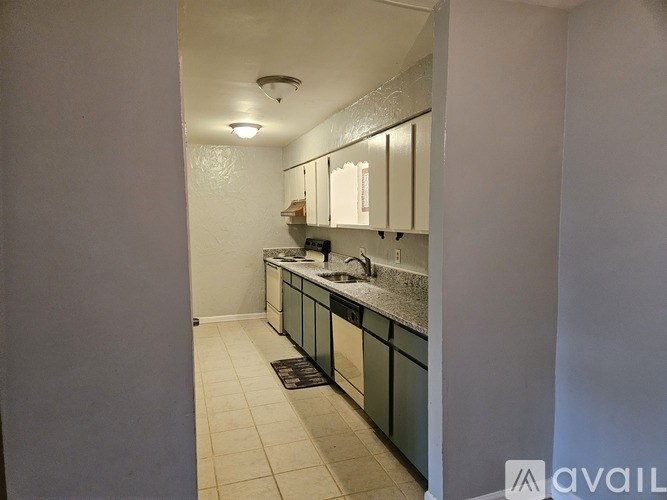 A kitchen with white cabinets and a black mat on the floor.