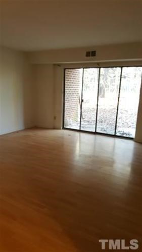 Empty room with wooden floor and sliding glass doors.