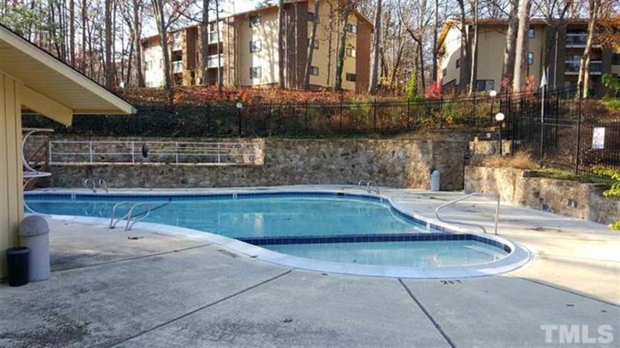 A small residential pool surrounded by a stone wall and a fence.