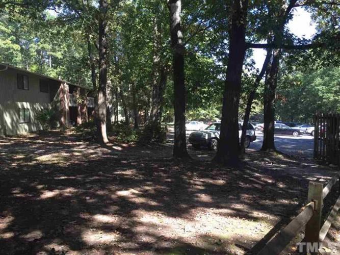 A backyard with a tree and a house in the background.