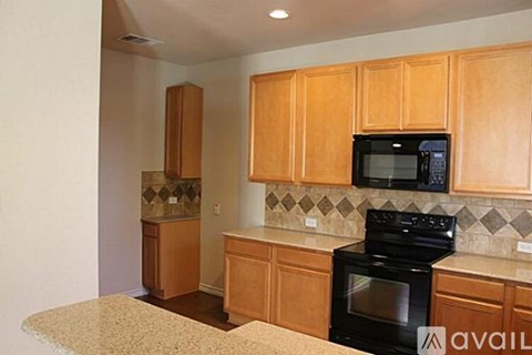 A kitchen with wooden cabinets and a black microwave above the stove.