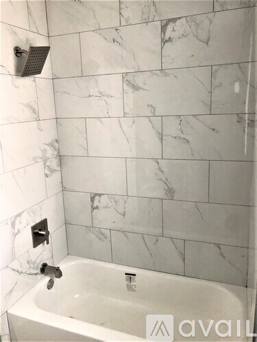 A white bathtub with a shower head and faucet.