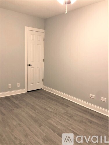 A room with a white door and grey flooring.