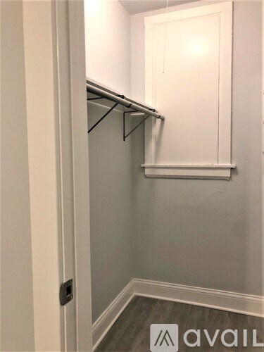 A white closet with a shelf and a black hanger.