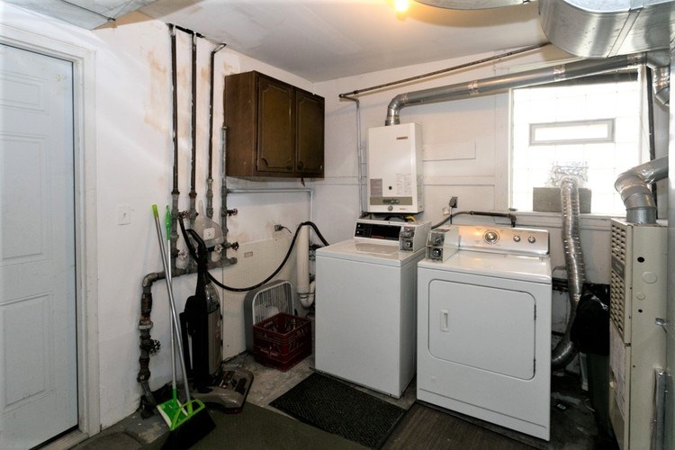 A clean, white-walled room with a washer and dryer, a vacuum cleaner, and a mop.