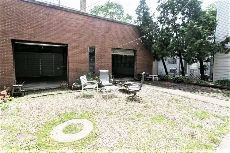 A backyard with a white chair and a circular garden bed.