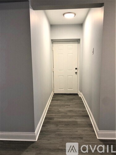 A hallway with a white door and grey walls.