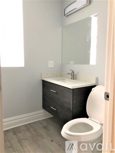 A bathroom with a toilet, sink, and mirror.