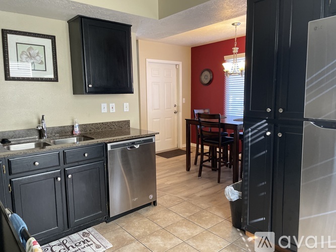 A kitchen with black cabinets and a red wall.