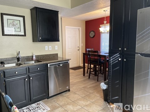 A kitchen with black cabinets and a red wall.