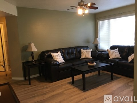 A living room with a black leather couch and a wooden coffee table.