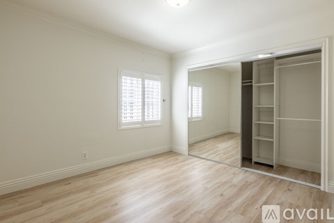 A room with wooden flooring and a large mirror on the wall.