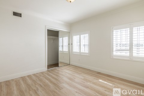 A room with a white door and windows with blinds.