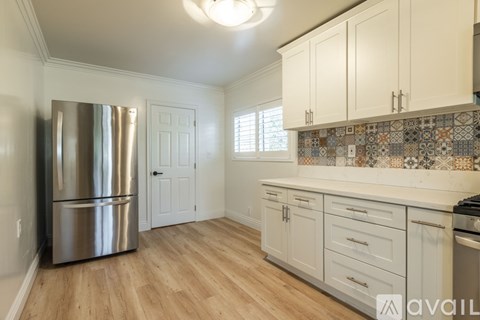 A kitchen with white cabinets and a stainless steel refrigerator.