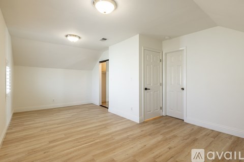 A room with wooden flooring and white walls, with a door on the right side.