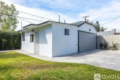 A white house with a grey garage door is for sale.