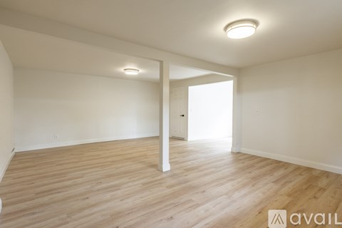 A spacious room with wooden flooring and white walls.