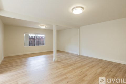 A spacious room with wooden flooring and a window.