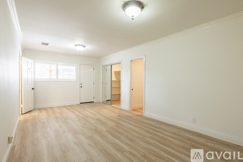 A spacious room with wooden flooring and white walls.