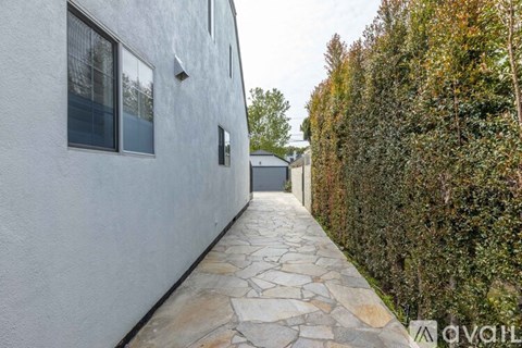 A white house with a stone pathway leading to a small building.
