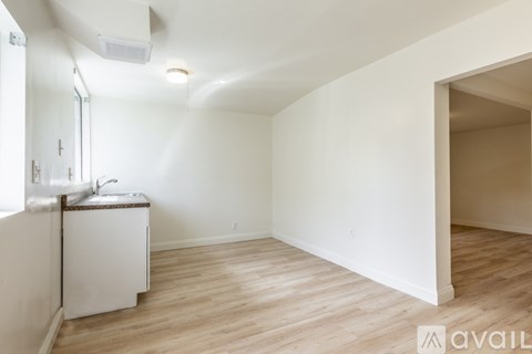 A small white kitchen with wood flooring and a window.