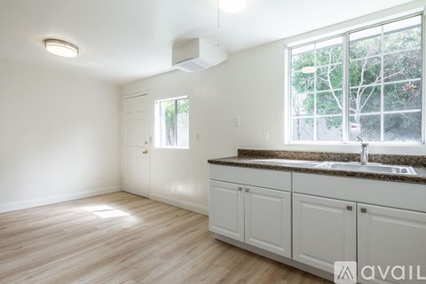 A kitchen with white cabinets and a window overlooking trees.