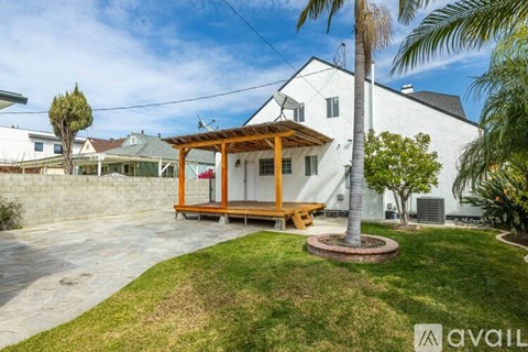 A white house with a wooden porch and a palm tree in the front yard.