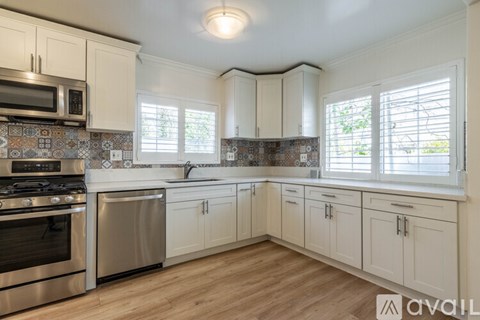 A kitchen with white cabinets and a stainless steel oven.