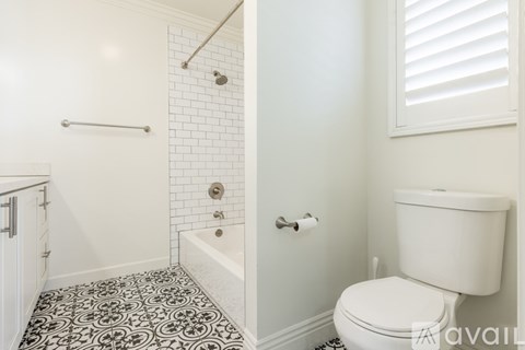 A white toilet sits next to a white bathtub in a bathroom with black and white tile flooring.