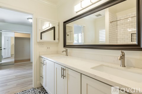 A bathroom with a sink, mirror, and wooden floors.