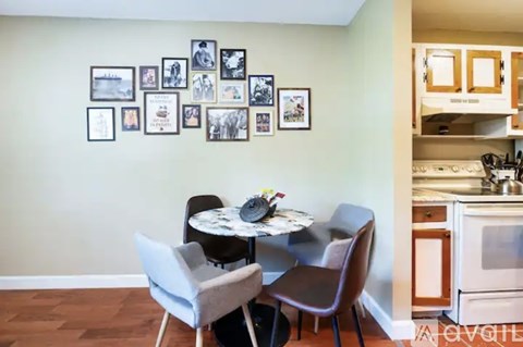 A dining room with a table set for two and a kitchen area with a stove.
