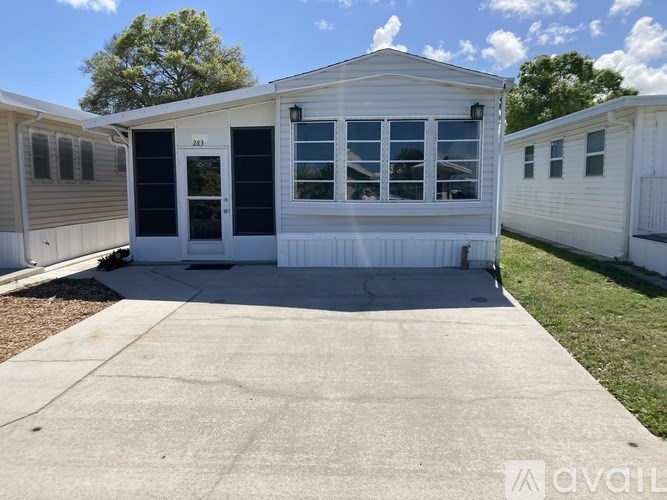 A white mobile home with a black door and windows is shown.