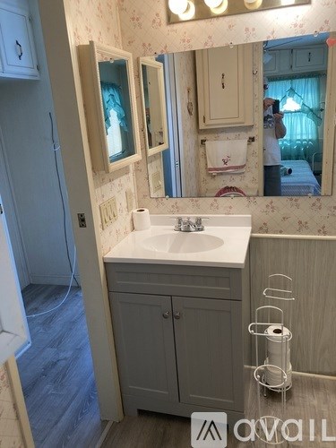 A bathroom with a sink, mirror, and cabinet.