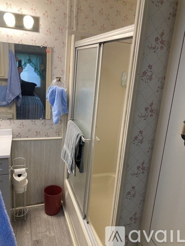 A bathroom with a toilet, a mirror, a towel, and a trash can.