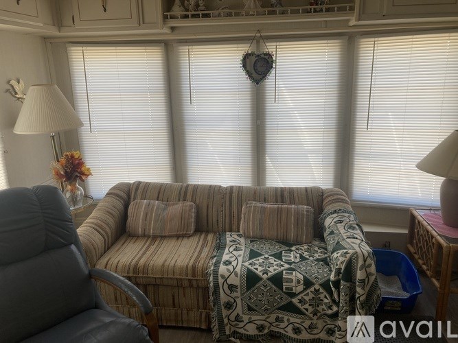A living room with a couch, chair, and window with blinds.