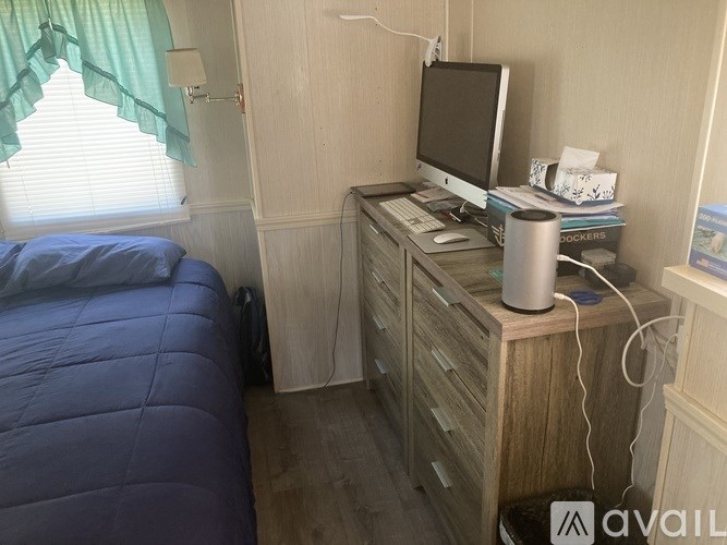 A bedroom with a bed, desk, and window.