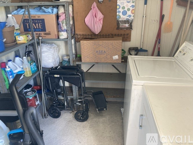 A cluttered storage area with a wheelchair and various items.