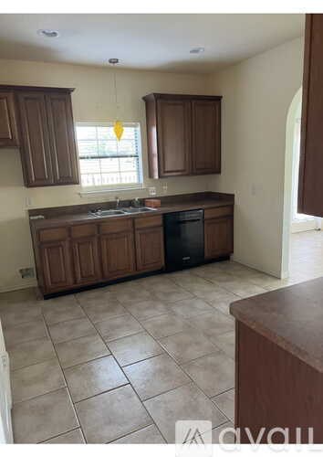 A kitchen with brown cabinets and a tile floor.