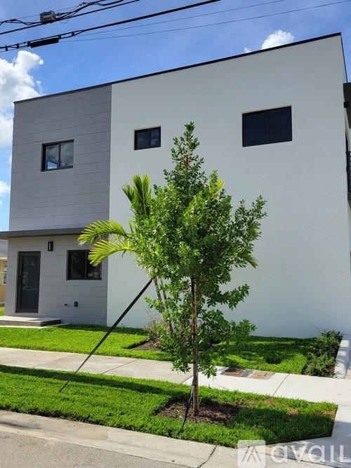 A white house with a tree in front.