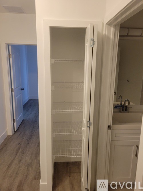 A white pantry with shelves and a door open to a bathroom.