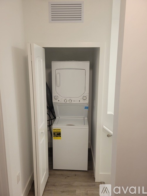 A small white washing machine is in a doorway.