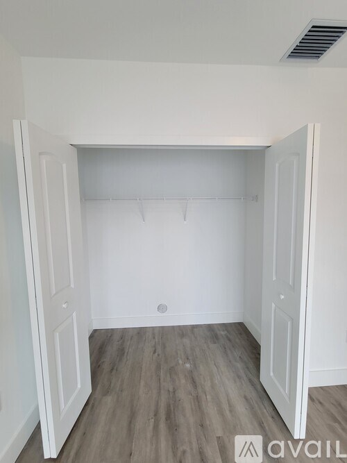 A white closet with a wooden floor and a white door.