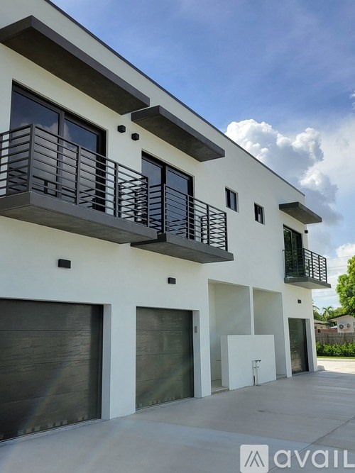 A modern two-story building with balconies and garage doors.