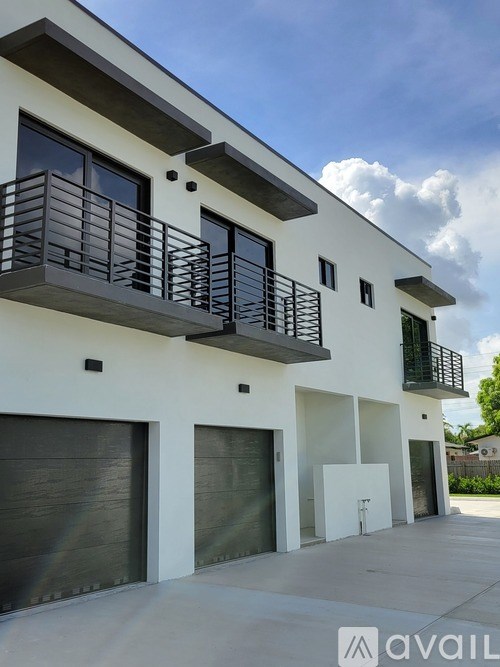 A modern two-story building with balconies and garage doors.